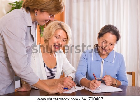 Two senior ladies signing documents at bank and smiling