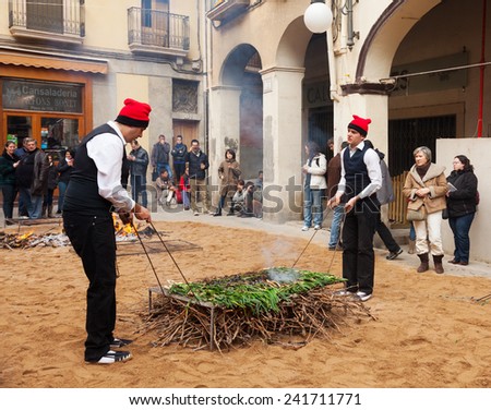 VALLS, SPAIN - JANUARY 26, 2014: Calcotada - popular gastronomical event. Men in traditional peasant dress cooking calsot on bonfire in Valls