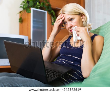 Crying senior blonde lady receiving bad news in internet