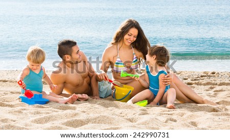 Young family with two children playing on the beach a summer day