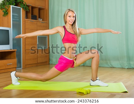 Positive smiling young woman working out with dumbbells at home