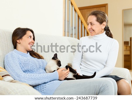 Happy mother and  teen daughter  talking on sofa at home