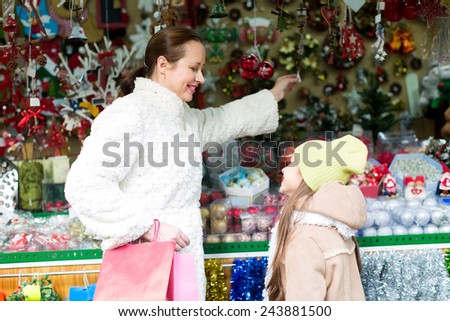 Adult mother with a daughter choose decorations for the Xmas tree. Focus on woman