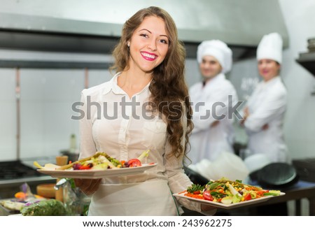 Team of chefs and young beautiful waiter at the restaurant kitchen