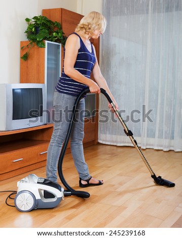 Photo of mature  woman cleaning living room