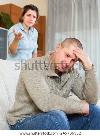 Family quarrel. Sadness man against unhappy young woman in living room