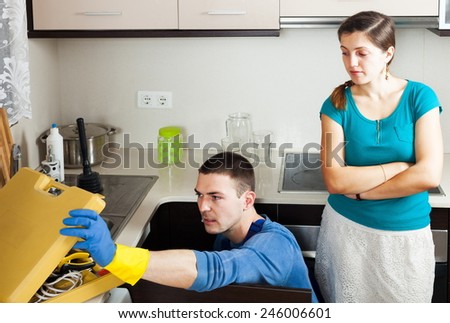 Woman watching as plumber working with water lines