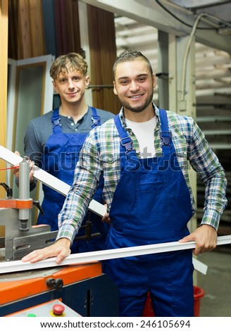 Positive people working together on a machine in factory