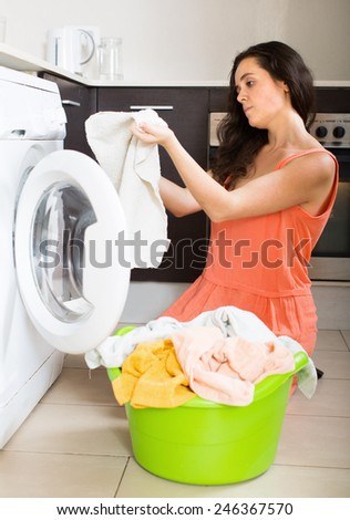 Home laundry. Unhappy  girl using washing machine at home