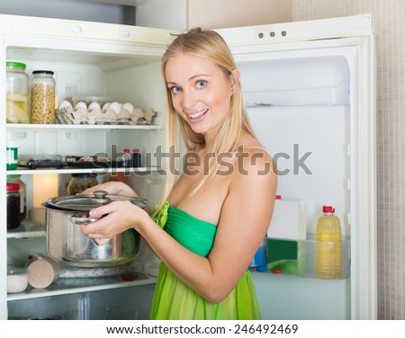 Happy hungry girl with pan near fridge  at her home