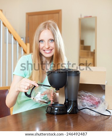 Young blond with new electric coffee maker at home in living room