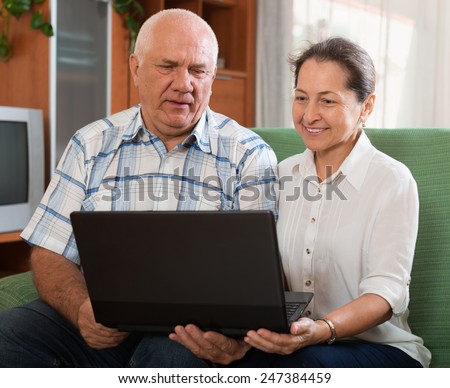 Happy mature couple  with computer  at table in home