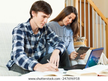 Couple unhappy students learning for exam with electronic book in home interior