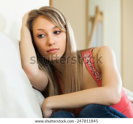Sad and lonely woman sitting on couch at home