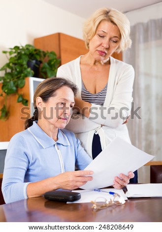 Frustrated elderly ladies checking invoices at office.Focus on the left woman