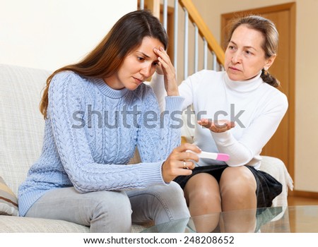 Elderly woman and uptight young girl with a pregnancy test