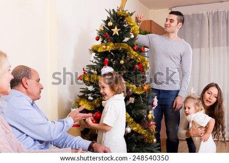 big multigenerational happy family near the Christmas tree.Focus on girl with white bow