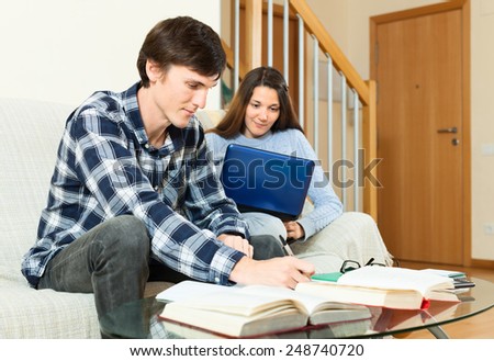 Students guy and girl preparing for exam with books and notebook at home