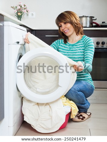 Happy girl in green using washing machine at home