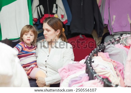 mother and  baby girl chooses wear at clothes shop