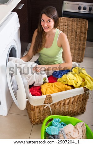 Young smiling housewife with linen basket in domestic kitchen