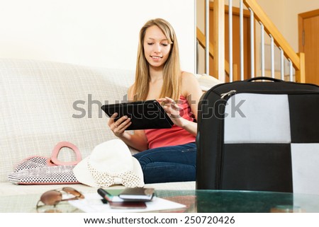 Happy young woman planning a vacation and journey on a tablet   in home interior