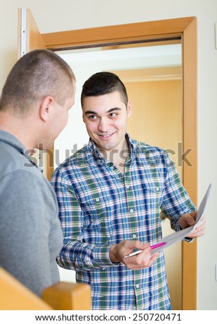 Smiling service employee asking tenant to sign a document at the doorway