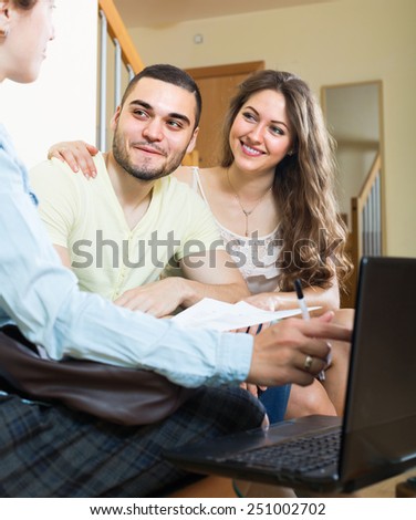 Happy couple answer questions of social worker in the living room at home