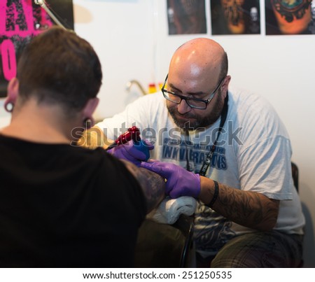 BARCELONA, SPAIN - OCTOBER 3, 2014: Tattoo master doing  tattoo on client hand. The 17th edition of The Barcelona Tattoo Expo in Fira de Barcelona
