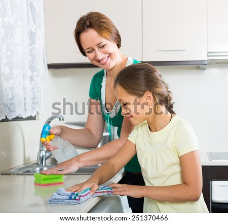 Portrait of smiling girl and american mom tidy kitchen up