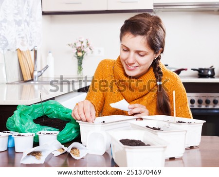 Woman planting seeds in ground at table in kitchen