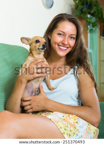 Happy smiling girl holding Russkiy Toy Terrier indoor