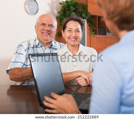 Mature couple answer questions of agent with notebook in  office