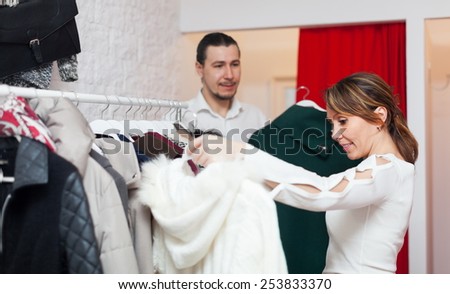 Smiling adult couple choosing clothes at clothing shop