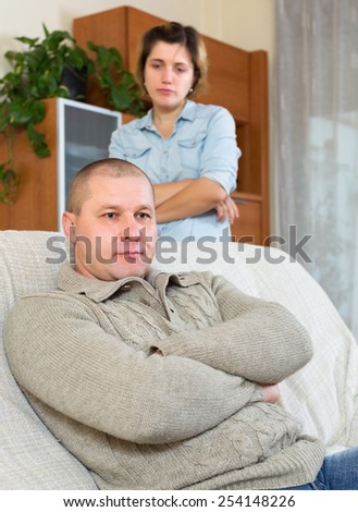 Family quarrel. Sadness man against unhappy young woman in living room at home