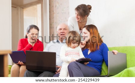 Happy family of with various portable computers on sofa at home