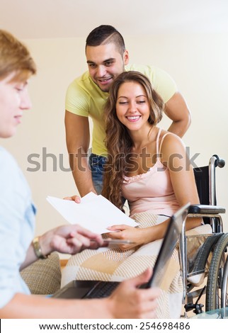 Happy couple with disabled wife talking with female banking clerk indoor