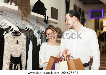 cheerful couple with shopping bags at clothing shop