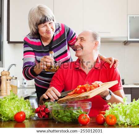 happy loving elderly couple cooking with tomatoes in home kitchen
