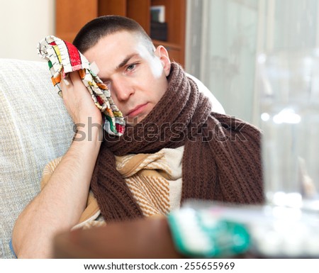 Young guy covered with plaid and scarf stuping  towel to head