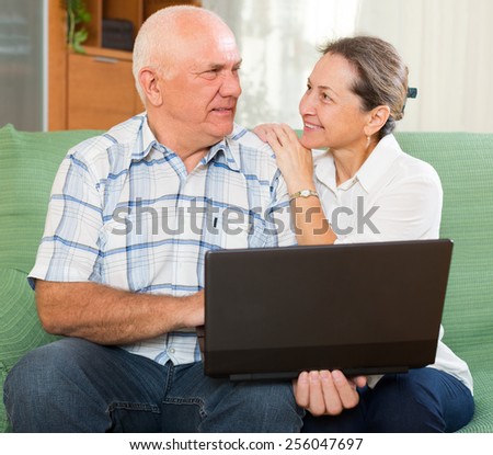 Happy elderly family using laptop at home