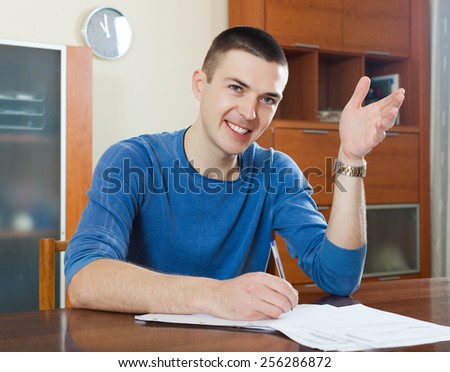 serious guy staring financial documents at table in home interior