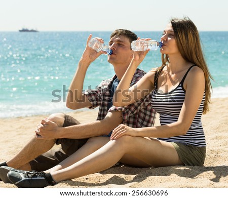 Thirsty young couple enjoying a refreshing drink of water at sunny day