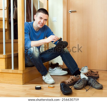 Happy man sitting on stairs and cleaning boots