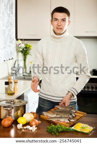 Man is thinking how to cook fish in fryingpan at kitchen