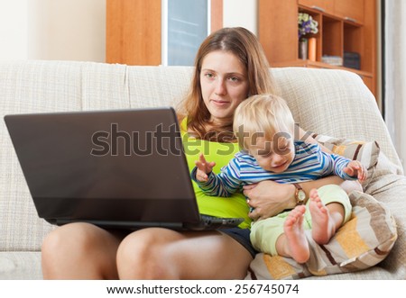 mother with crying baby working online with laptop