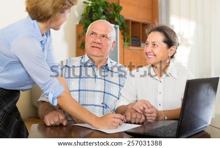 Senior couple talking with employee with laptop at home. Focus on man