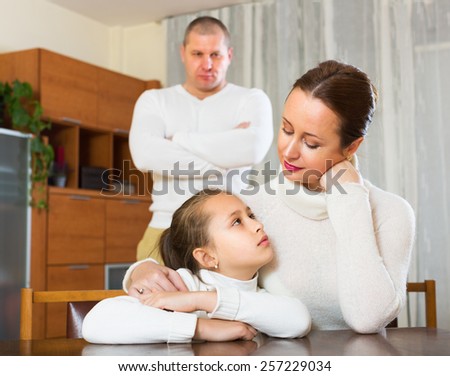 Daughter comforting sad mother at home and angry father