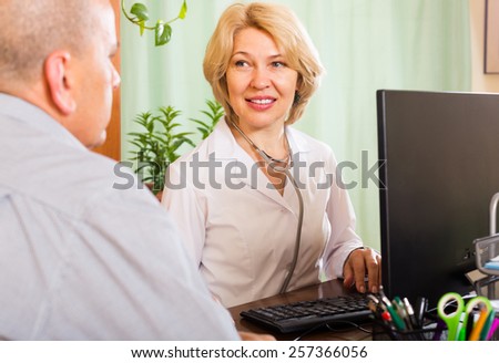 Smiling mature female therapist examining elderly man in clinic office