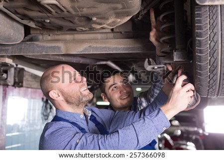 Two smiling  man fixing car tire leak